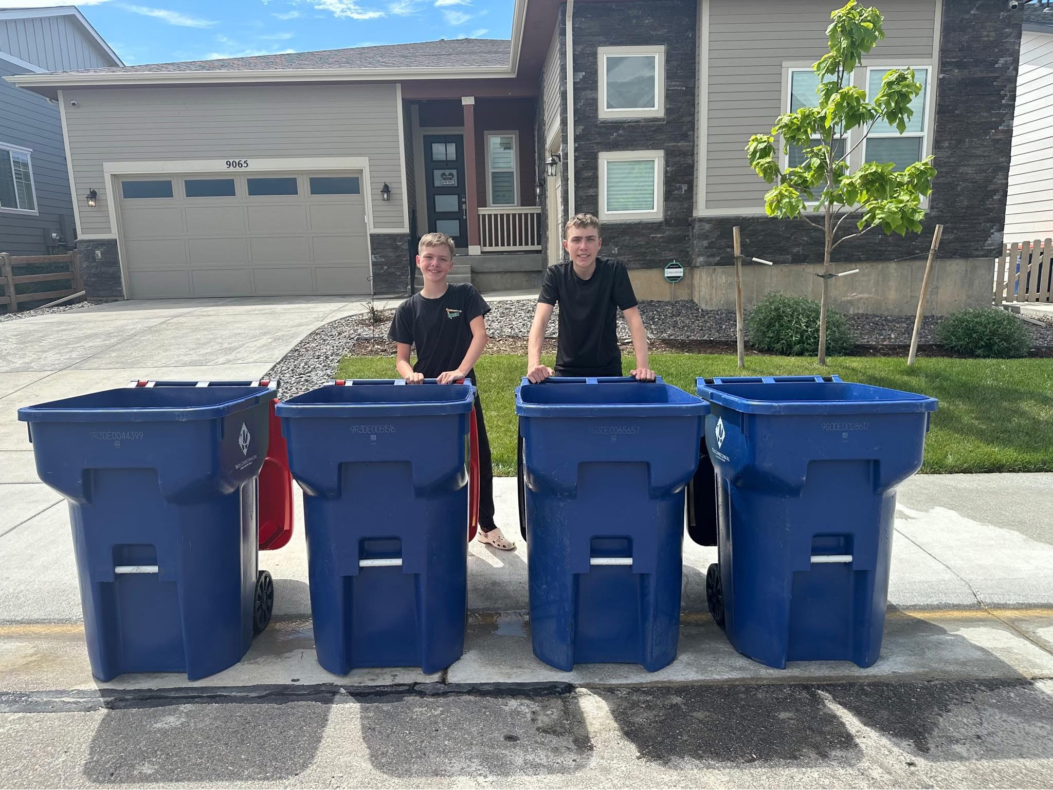 Ben and Noah, the two brothers behind Todd Bin Squad, standing with cleaned bins in Sterling Ranch